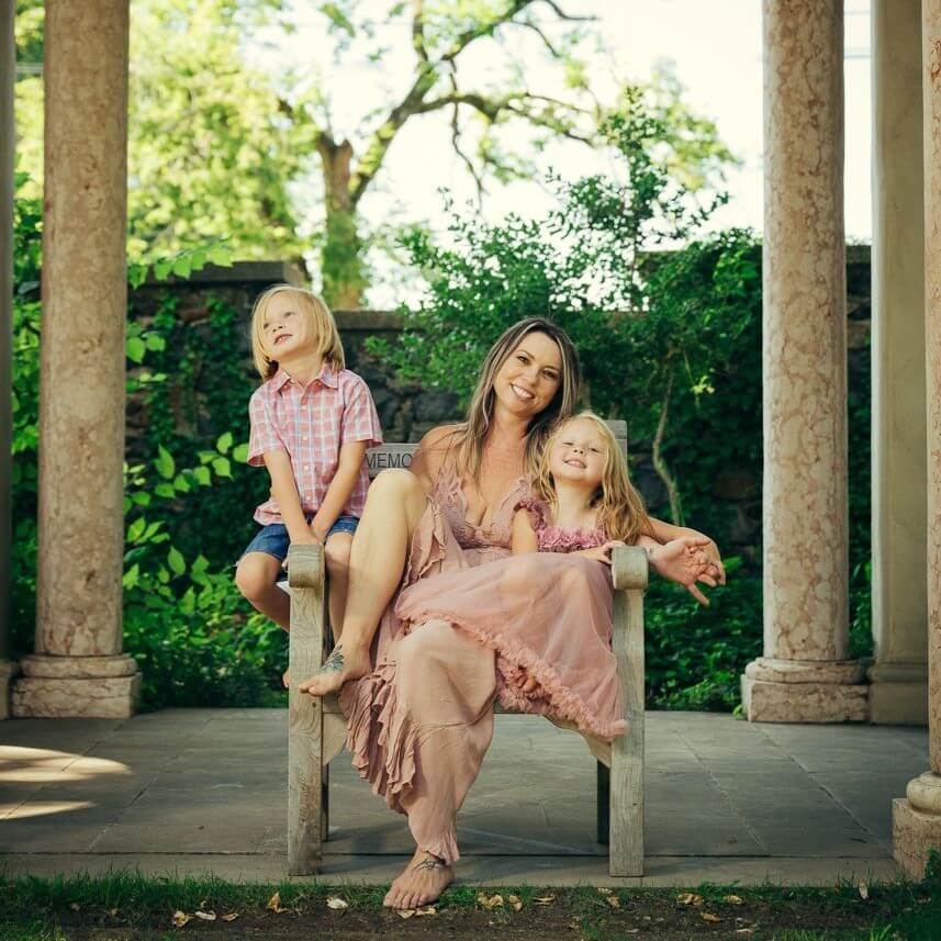 An image of Sarah and her two young children, a boy and girl, sitting in a chair, smiling.